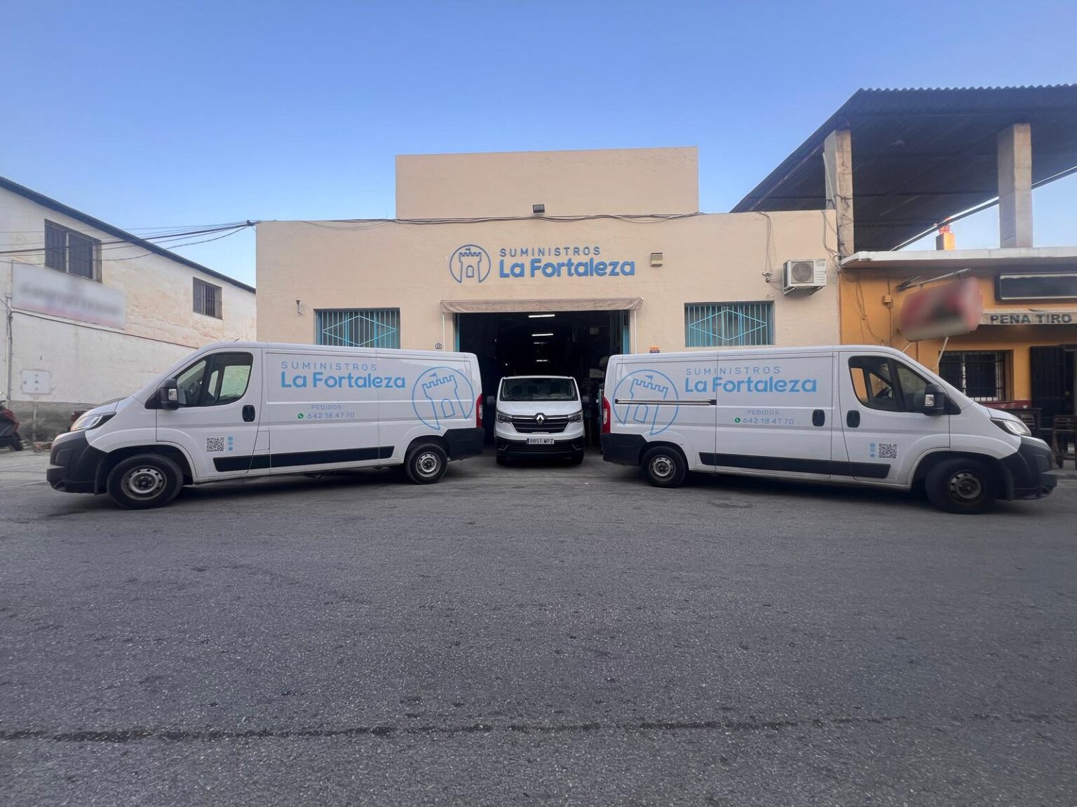 Furgonetas de reparto de Suministros La Fortaleza frente a sus instalaciones